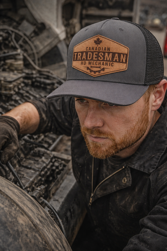 Man wearing a 'Canadian Tradesman, No Mechanic' cap in an outdoor setting.