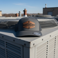 Tradesman cap on an air conditioning unit with buildings in the background