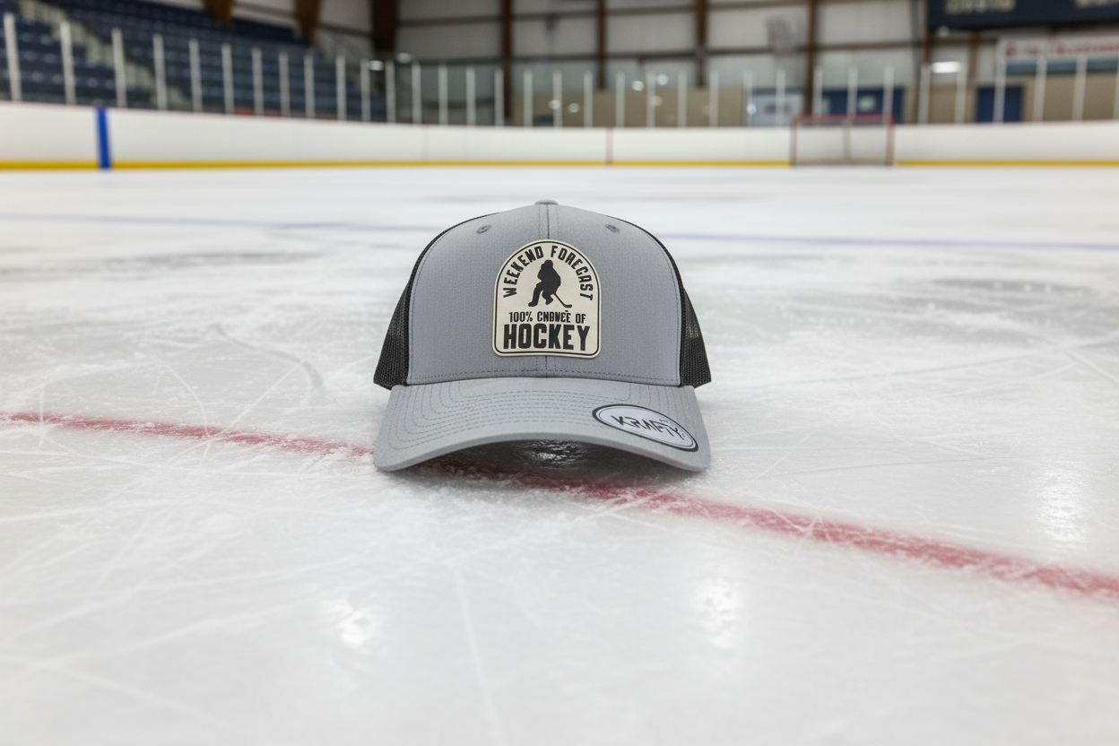 A gray trucker hat with a patch on the front that reads 'Weekend Forecast 100% chance of Hockey' and a logo on the brim.